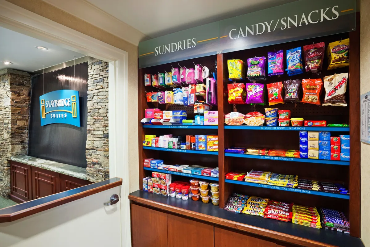 A casual snack area with a well-stocked shelf of treats, clear signage, and a rustic stone wall. The space suggests ease and convenience for families grabbing a quick bite after a busy day or stocking up before heading out to explore.