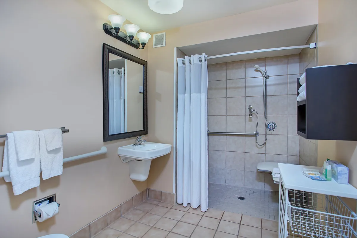 A calm, spa-inspired bathroom with a stylish mirror, modern sink, spacious shower area, and towel rack. The ambiance feels fresh and relaxing, suggesting quiet moments of self-care after a busy day in the city.