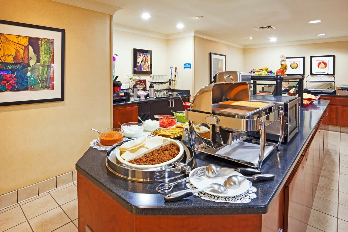 An abundant buffet spread with a stylish coffee station and art-adorned walls, where guests dine and socialize in a warm, communal atmosphere. The arrangement of variety in the buffet and the inviting seating highlights opportunities for both hearty meals and casual interaction.